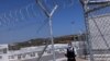 A private security employee stands guard during the inauguration of a closed-type migrant camp on the island of Samos, Greece, Sept. 18, 2021. 