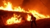 A firefighter carries a drip torch as he ignites a backfire against the Hughes Fire burning along a hillside in Castaic, Calif., Jan. 22, 2025.