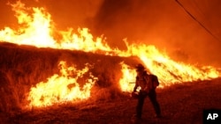 A firefighter carries a drip torch as he ignites a backfire against the Hughes Fire burning along a hillside in Castaic, Calif., Jan. 22, 2025.