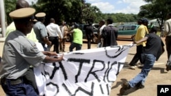 A Zimbabwean policeman struggles to confiscate a banner from a human rights activist on March 22, 2013.