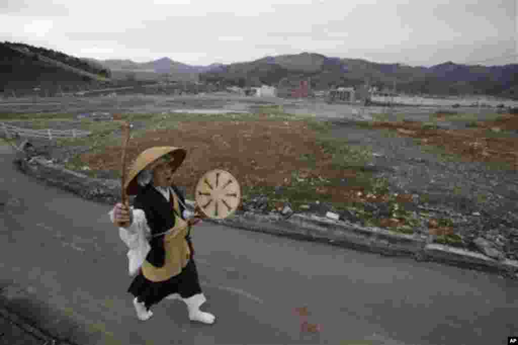 A Buddhist monk chants sutras as he walks through a neighborhood destroyed by the March 11 earthquake and tsunami in Onagawa, Miyagi Prefecture, Friday, March 9, 2012, two days before the one-year anniversary of the disaster. (AP Photo/Shizuo Kambayashi)