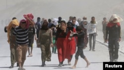 Displaced people from the minority Yazidi sect march in a rally at the Iraqi-Turkish border crossing in Zakho district of the Dohuk Governorate of the Iraqi Kurdistan province August 17, 2014.