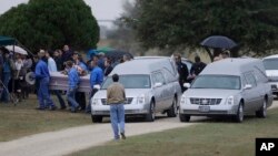 A casket is removed from one of two hearses during a grave side service for Richard and Therese Rodriguez at the Sutherland Springs Cemetery in Sutherland Springs, Texas, Nov. 11, 2017.
