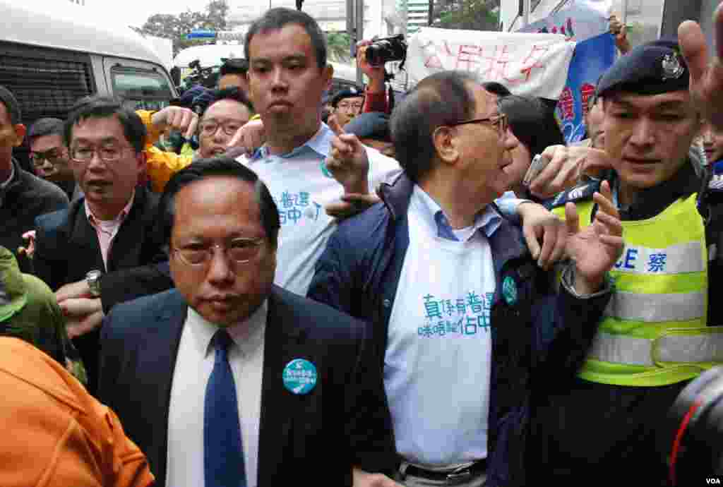 民主黨立法會議員何俊仁(左)與前黨主席楊森(中)在警員護送下步行返回辦公室