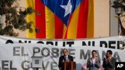 FILE - Catalan regional President Quim Torra, center, applauds in front of a large Catalonia independence flag during a rally in Sant Julia de Ramis, Spain, Oct. 1, 2018. Tensions appear to be growing between the two main Catalan secessionist parties.