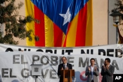 FILE - Catalan regional President Quim Torra, center, applauds in front of a large Catalonia independence flag during a rally in Sant Julia de Ramis, Spain, Oct. 1, 2018.