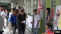 选民在台北一处投票站排队等候投票