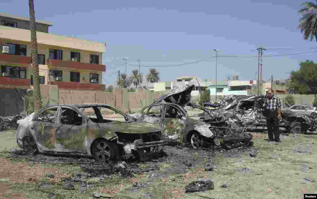 A man looks at damaged vehicles at the site of a car bomb attack in Baghdad's Kadhimiya district, September 30, 2013.