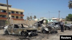 Seorang pria mengamati mobil-mobil yang hancur akibat serangan bom di distrik Kadhimiya, Baghdad (30/9).