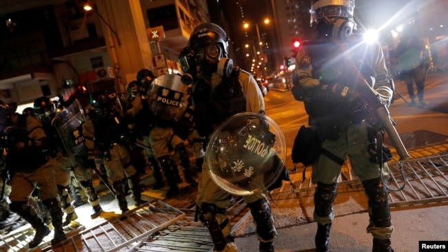 香港防暴警察在寻找抗议者时通过一个路障。（2019年10月7日）