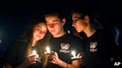 Attendees comfort each other at a candlelight vigil for the victims of the shooting at Marjory Stoneman Douglas High School, Feb. 15, 2018, in Parkland, Fla. 