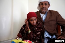 Saida Ahmad Baghili, 18, who has been affected by severe malnutrition, sits with her father at a hotel in Sanaa, Yemen, Dec. 4, 2016.