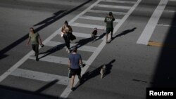 Gente cruzando una calle de Miami Beach y practicando la "distancia social", la medida impuesta por las autoridades para frenar la propagación del coronavirus.