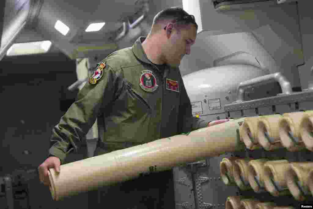 A Naval aircrewman unloads a Sonobuoy from a rack onboard a P-8A Poseidon during a search mission to locate Malaysia Airlines flight MH370 in the Indian Ocean, in this U.S. Navy handout photo taken April 10, 2014.