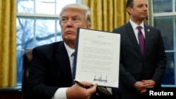 U.S. President Donald Trump holds up the executive order on the reinstatement of the Mexico City Policy after signing in the Oval Office of the White House in Washington, Jan. 23, 2017. 