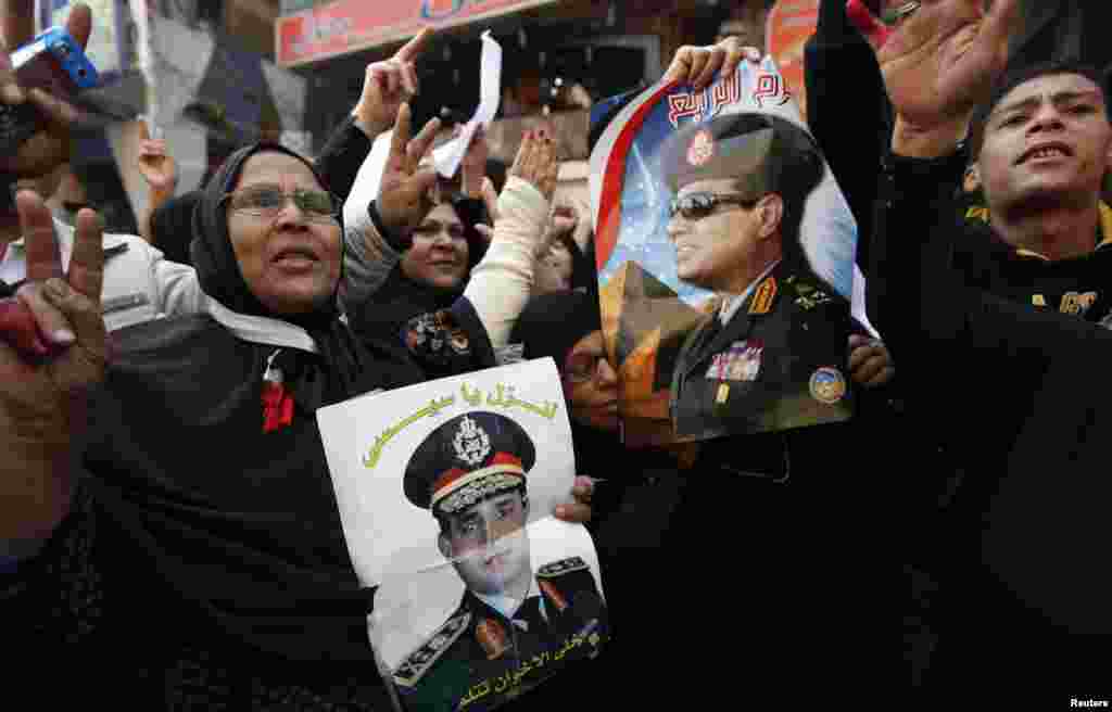 Para pendukung tentara Mesir dan kepala angkatan darat Jenderal Abdel Fattah el-Sissi memegang poster dan meneriakkan slogan-slogan di depan sebuah gedung yang rusak di komplek pengadilan menyusul sebuah ledakan di Imbaba, sebelah utara Kairo (14/1).