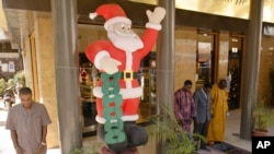 Des musulmans assistent à la prière du vendredi après-midi à côté d'un Père Noël gonflable près d’une boulangerie dans le centre de Dakar, au Sénégal, 16 décembre 2005.