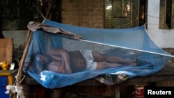 Laborer sleeps on a makeshift bed covered with a mosquito net on a hot summer morning, New Delhi, May 23, 2013.