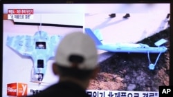 FILE - A man watches a TV news program showing unmanned drones, at the Seoul Railway Station in Seoul, South Korea, Wednesday, April 2, 2014