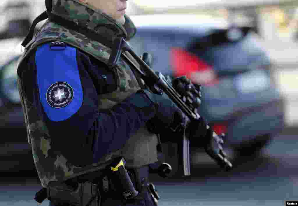 A heavily armed Swiss customs officer stands guard at the Swiss-French customs post of Bardonnex near Geneva, Switzerland. Geneva raised its alert level on Thursday and said it was looking for suspects who, according to national officials, had possible links to terrorism.