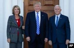 President-elect Donald Trump and Vice President-elect Mike Pence and Betsy DeVos pose for photographs at Trump National Golf Club Bedminster clubhouse in Bedminster, N.J., Saturday, Nov. 19, 2016.