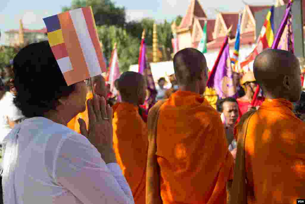 A Cambodian woman hold a Buddhist flag at the royal parade in Phnom Penh. (Nov Povleakhena/VOA Khmer)