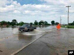 A pickup evacuates from an area in north Jefferson City, Miss., as floodwaters from the Missouri River rise over the road May 24, 2019. The flooding come as residents are still cleaning up from a powerful tornado that hit the state's capital city Wednesday.