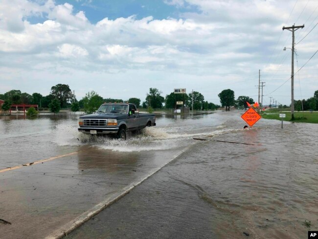 A pickup evacuates from an area in north Jefferson City, Miss., as floodwaters from the Missouri River rise over the road May 24, 2019. The flooding come as residents are still cleaning up from a powerful tornado that hit the state's capital city Wednesday.