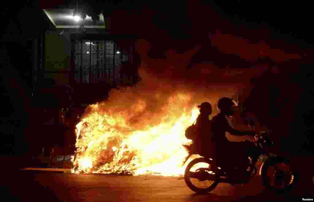 A motorcycles passes a bonfire during a protest by members of the "Free Pass" movement to demand zero tariffs in the Brazilian public transport system in Rio de Janeiro, Feb. 6, 2014.