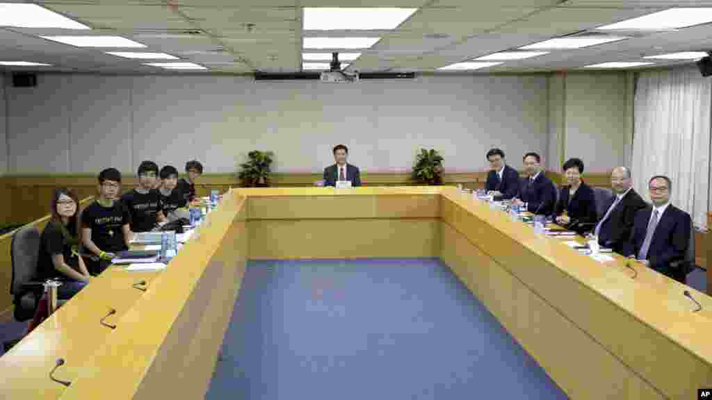 Hong Kong government officials line the right side of the table, Lingnan University president Leonard Cheng, center, and student leaders line the left side of the table as talks between Hong Kong officials and students begin, Oct. 21, 2014.