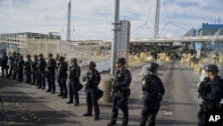 Agentes de la Oficina de Aduanas y Protección Fronteriza de Estados Unidos montan guardia en el cruce fronterizo de San Ysidro en la frontera entre México y Estados Unidos, vistos desde Tijuana, México.