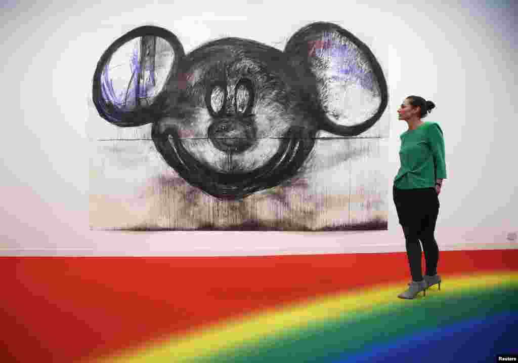 A visitor poses with artist Joyce Pensato&#39;s artwork &quot;Mickey for Micky&quot; at the Frieze Art Fair in London. 