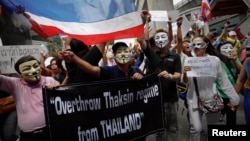 Protesters wearing masks shout slogans as they march though Bangkok's shopping district, June 2, 2013. 