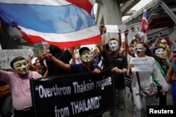 Protesters wearing masks shout slogans as they march though Bangkok's shopping district, June 2, 2013.