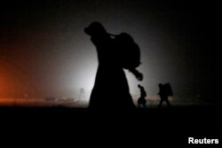 FILE - A group of migrants who said they were from Djibouti and Somalia walk along railway tracks after crossing the Canada-U.S. border in Emerson, Manitoba, Canada, March 27, 2017.