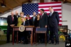 President Barack Obama, surrounded by members of Congress, signs the Farm Bill, Feb. 7, 2014, at Michigan State University in East Lansing, Michigan.