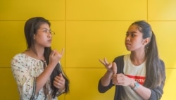 Seng Theary (left) talk to her colleague, Koy Socheata, who has a hearing disability, using sign language at their workplace, Socials Coffee, in Phnom Penh, Cambodia, May 23, 2020. (Hean Socheata/VOA Khmer)