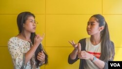 Seng Theary (left) talk to her colleague, Koy Socheata, who has a hearing disability, using sign language at their workplace, Socials Coffee, in Phnom Penh, Cambodia, May 23, 2020. (Hean Socheata/VOA Khmer)