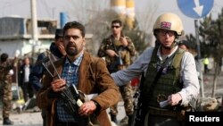 A British security official (R) escorts a survivor from the wreckage of a British embassy vehicle after a suicide attack in Kabul, November 27, 2014.