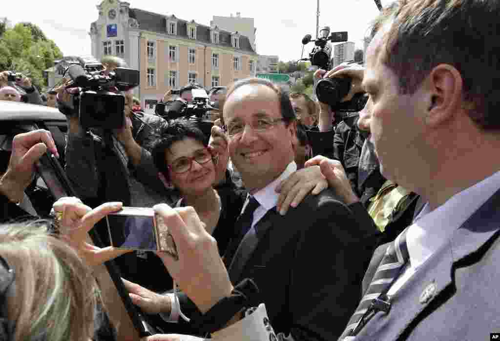 Socialist Party candidate for the presidential election Francois Hollande poses with residents after visiting a polling station near Tulle, central France, May 6, 2012. (AP)