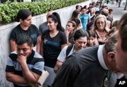 Hermelindo Che Coc, left, from Guatemala waits in line prior to a required check-in with immigration enforcement authorities in downtown Los Angeles, July 10, 2018. Che Coc says his 6-year-old son feared he was dead after U.S. authorities separated the pair on the U.S.-Mexico border. Che Coc, said that they were split up after crossing into Texas in May. He says authorities told him he would be detained and his son was sent to a shelter in New York.