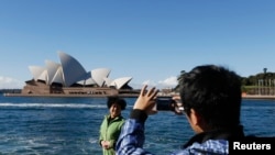 Seorang turis China berpose di depan Sydney Opera di Sydney (Foto: dok.)