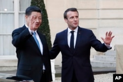 French President Emmanuel Macron, right, and his Chinese counterpart Xi Jinping wave to journalists after a meeting at the Elysee Palace, in Paris, March 25, 2019.