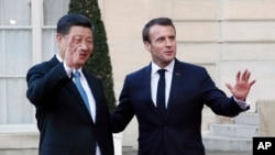 French President Emmanuel Macron, right, and his Chinese counterpart Xi Jinping wave to journalists after a meeting at the Elysee Palace, in Paris, March 25, 2019.