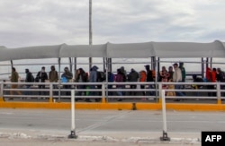 FILE - Migrants from Cuba, Venezuela and Central America queue at the Paso del Norte International Bridge in Ciudad Juarez, Chihuahua state, Mexico, to cross the border and request political asylum in the United States, Jan. 9, 2019.