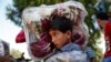 一名加沙少年扛着捐赠毯子和其他离家逃亡的巴勒斯坦难民一道前往一所联合国学校避难。（2014年7月23日）