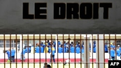 Prisoners are seen at the Makala prison in Kinshasa from behind the bars of the windows of a court room, on December 18, 2012.