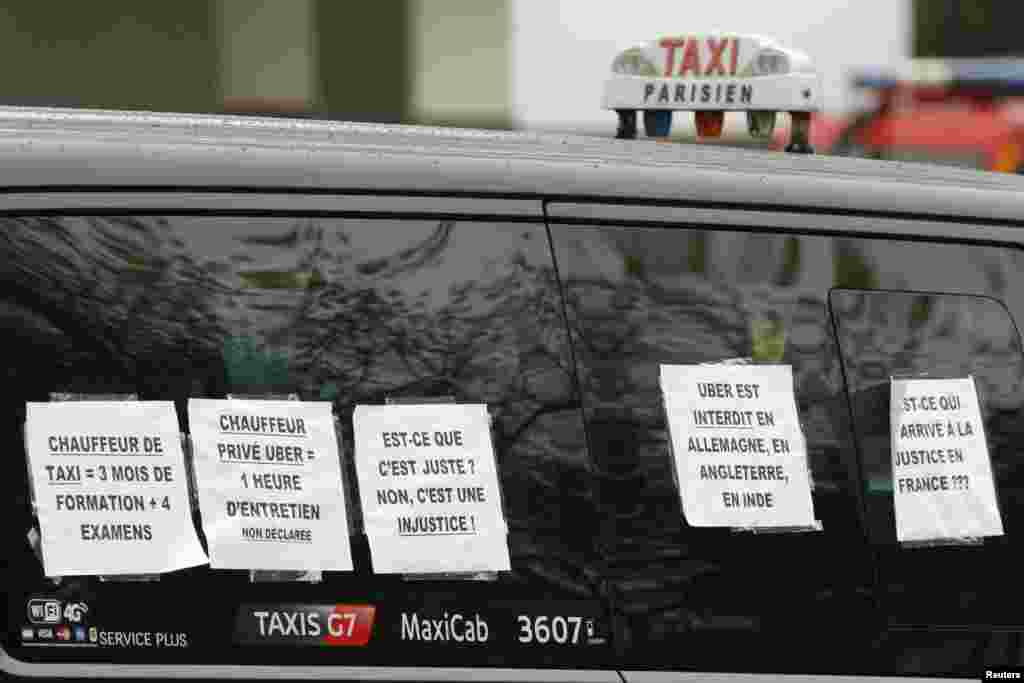 A striking Paris taxi displays signs reading "Uber is forbidden in Germany, Britain and India" during a demonstration over the Paris ring road, Dec. 15, 2014.