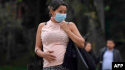 A pregnant woman wears a face mask as a preventive measure against the spread of the new coronavirus, COVID-19, as she waits for the bus in Bogota, on March 16, 2020.