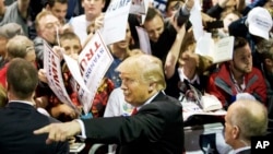 Republican presidential candidate Donald Trump gestures as signs autographs at a campaign event in Atlanta, Feb. 21, 2016.
